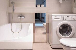 A modern bathroom with a bathtub, a washing machine, and a toilet. - Antique 1-bed apartment (Kraków – Old Town)
