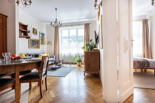 Une pièce bien éclairée comprenant un coin repas, un canapé, un lit et une grande fenêtre avec des rideaux.