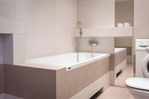 Une salle de bain moderne équipée d’une baignoire, de toilettes et d’un lave-linge.