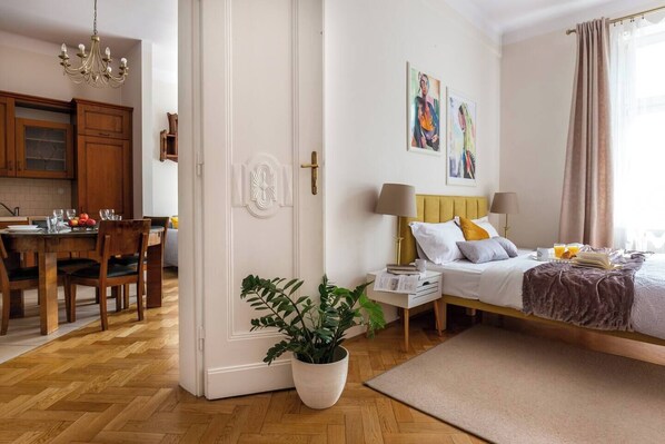 A hotel room with a bed, bedside tables, a potted plant, and artwork on the wall. - Antique 1-bed apartment (Kraków – Old Town)