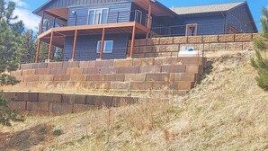Ein zweigeschossiges Haus mit einem Balkon und einer Steinmauersicherung.