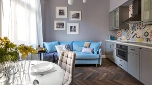 A modern kitchen with a herringbone floor, a blue sofa, and a dining table set with glasses and plates. - Apartment Lavender - One Bedroom Apartment, Sleeps 4 (Kraków – Old Town)