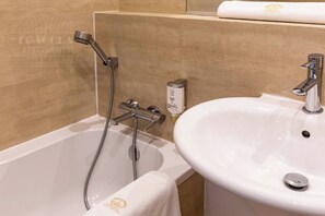 A bathroom with a bathtub, a sink, and a towel. - Sunny studio with balcony (Kraków – Old Town)