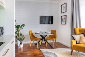 A modern living room with a round table, two yellow chairs, a sofa, a flat-screen TV, and a potted plant. - Sunny studio with balcony (Kraków – Old Town)