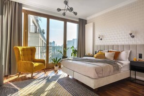 A modern bedroom with a large bed, a yellow armchair, a view of the city, and a balcony. - Sunny studio with balcony (Kraków – Old Town)