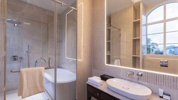Een moderne badkamer met een douchecabine van glas, een vrijstaand bad en een wastafel met een grote spiegel.