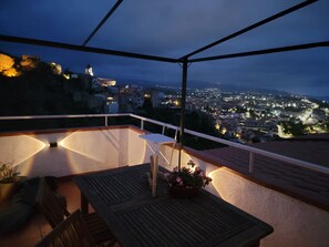 Una terraza en la azotea con una mesa, sillas y una planta en maceta.