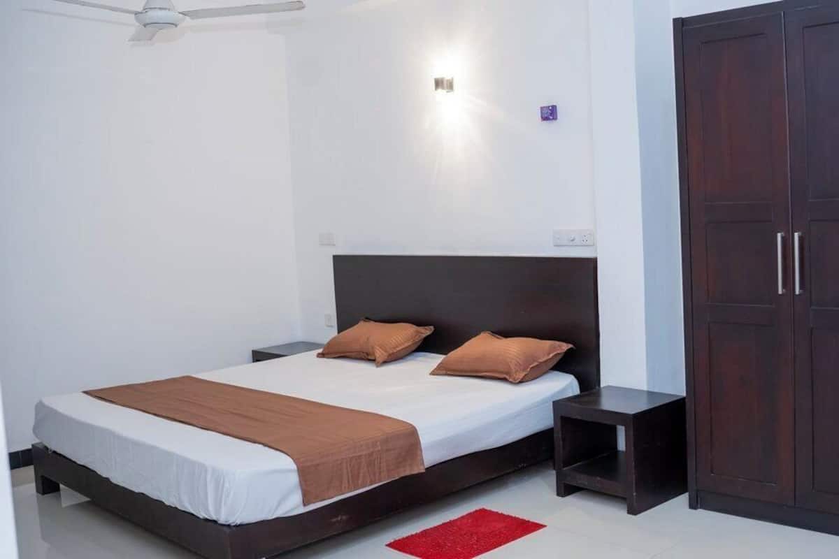 A bedroom with a bed, bedside tables, a wardrobe, and a ceiling fan.
