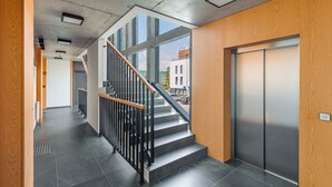 A modern interior with a staircase, elevator, and large windows. - Apartament Sun & Snow Kaszubska Bryza ll (Hel)