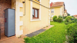 A residential building with a brick wall, a grey door, and a window with a white frame. - Apartamento Ruiloba-Comillas (Ruilobuca)