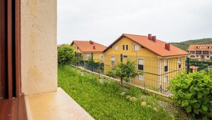 A yellow building with a red roof, surrounded by greenery and a metal fence. - Apartamento Ruiloba-Comillas (Ruilobuca)