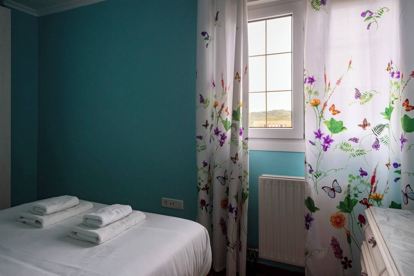 A bedroom with a bed, a window, and a radiator.