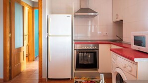 A kitchen with a refrigerator, oven, microwave, and washing machine. - Apartamento Ruiloba-Comillas (Ruilobuca)