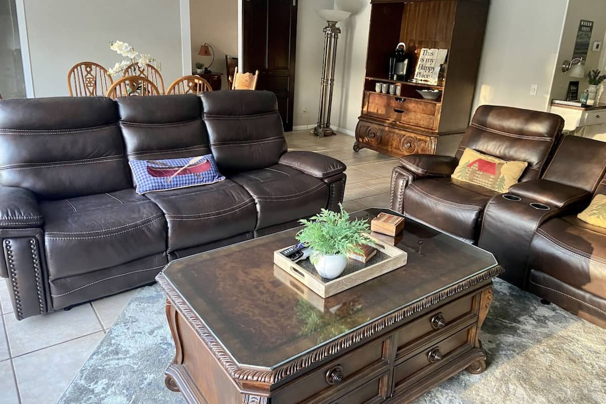 Un salon avec un canapé en cuir marron, une table basse en bois et un meuble en bois foncé.