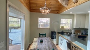 Un comedor con mesa de madera, sillas verdes y techo decorado con venados montados.