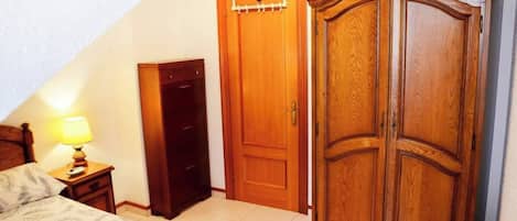 Un dormitorio con cama, mesita de noche con lámpara, armario y candelabro.