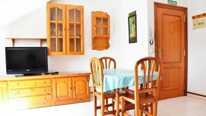 A dining area with a table set for two, wooden cabinets, a television, and a door labeled 'SALIDA'. - Apartamento en Somo con 2 plazas de garaje (Somo)