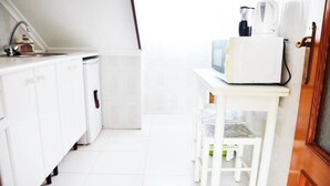 A kitchen with white cabinets, a small table, and a microwave. - Apartamento en Somo con 2 plazas de garaje (Somo)