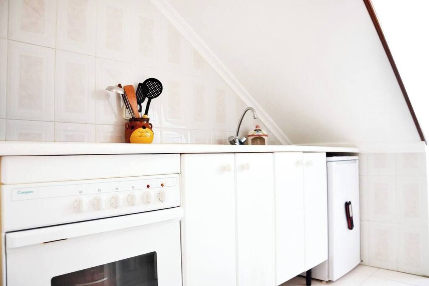 A kitchen with white cabinets, a stove, and a sink.