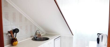 A small kitchenette with a sink, stove, and cabinets.