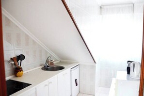 A small kitchenette with a sink, stove, and cabinets.
