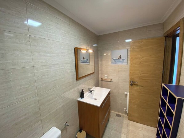 A modern bathroom with a wooden vanity, a mirror, and a sink.