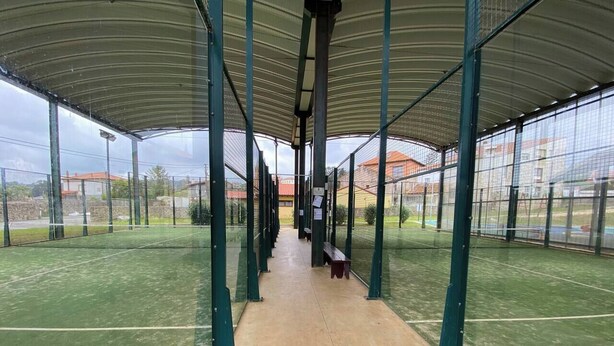 Un court de tennis intérieur doté d’une zone de sièges couverte et d’un filet au centre.