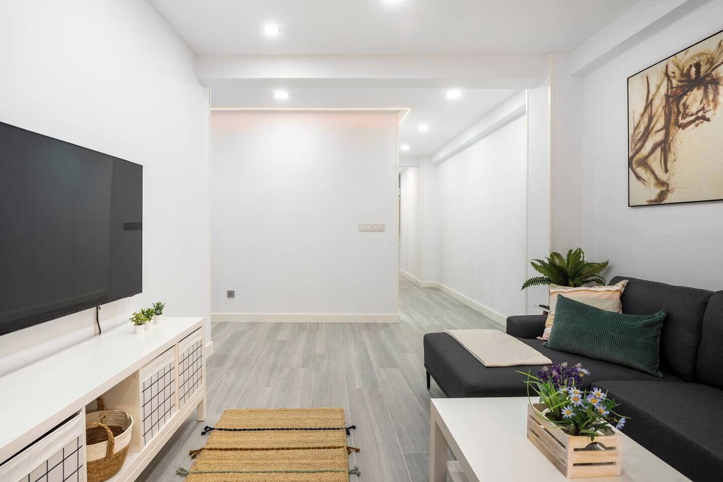 Un salon moderne avec un téléviseur à écran plat, un canapé, une table basse et une plante en pot.