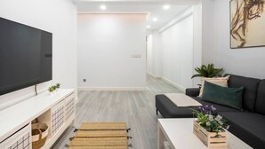 Un salon moderne avec un téléviseur à écran plat, un canapé, une table basse et une plante en pot.