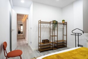 Une chambre moderne avec un lit, une armoire en bois, une chaise et une plante suspendue.