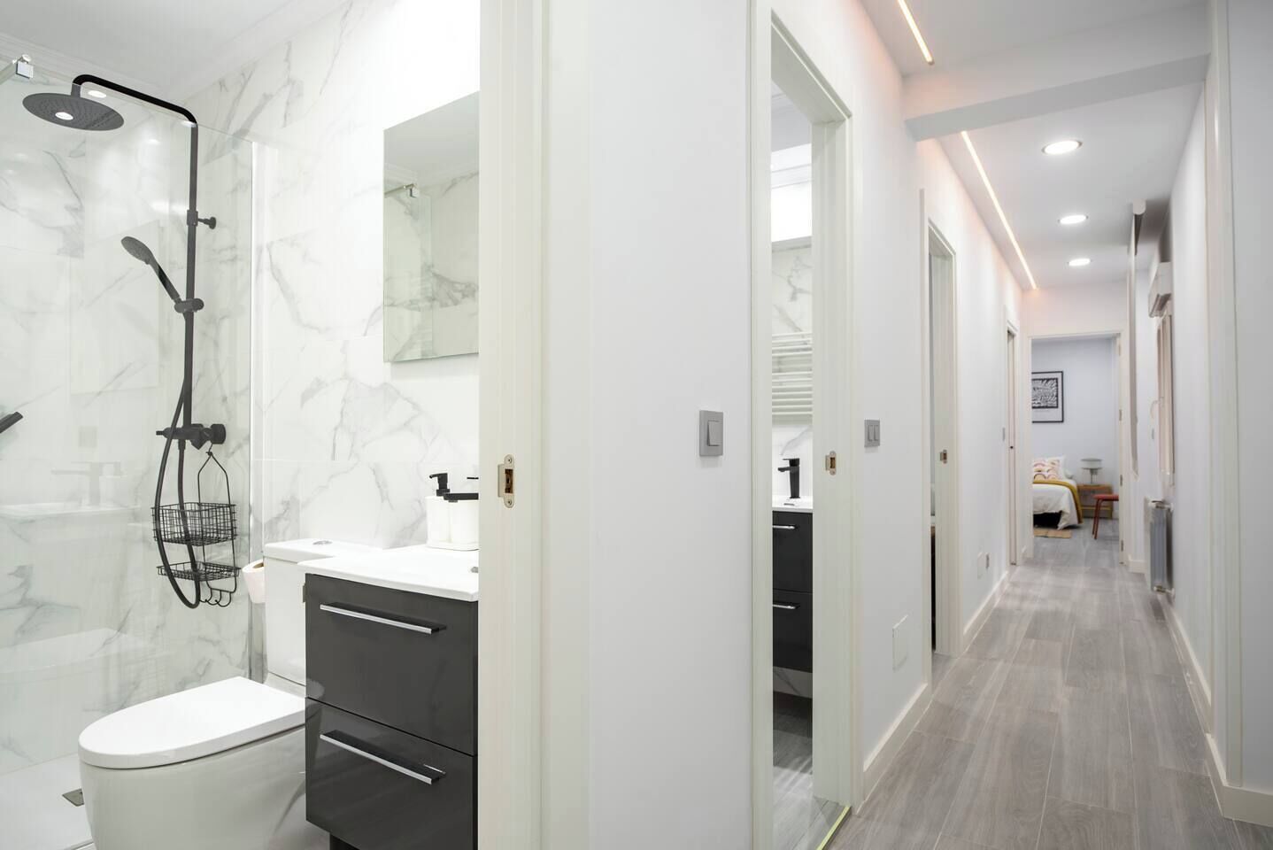 Een moderne badkamer met douche, toilet en wastafel.