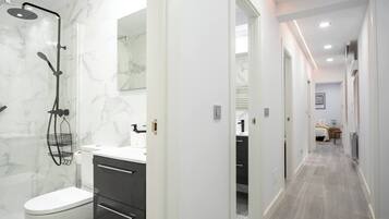Een moderne badkamer met douche, toilet en wastafel.