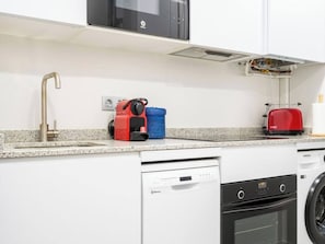 A kitchen with a dishwasher, oven, and a red toaster on the countertop.