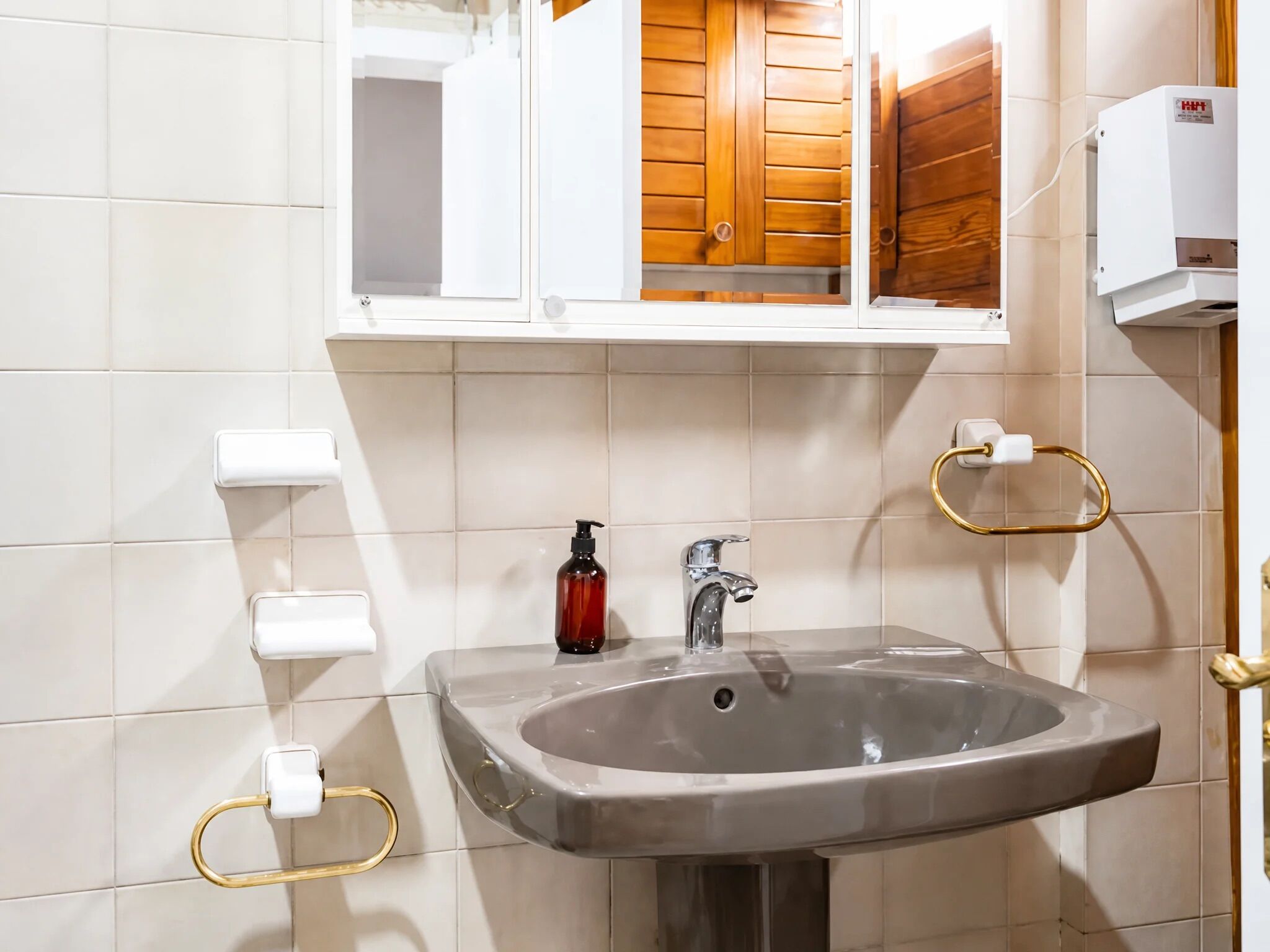 Un baño con lavamanos, espejo y armarios de madera.