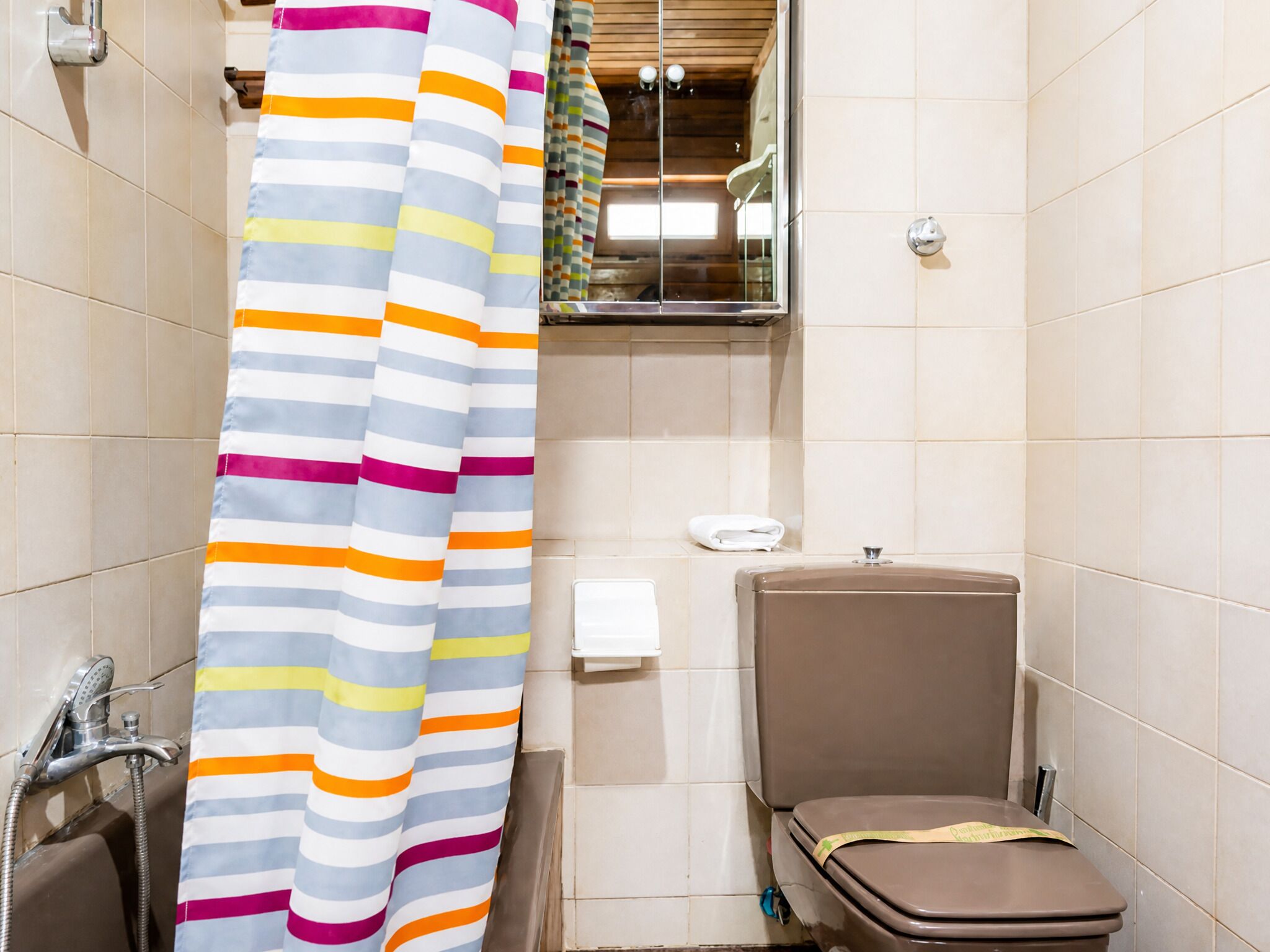 Et badeværelse med bruseforhæng, toilet og et håndklædestativ.