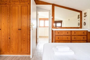 Une chambre à coucher avec une armoire en bois, un grand miroir et un lit soigneusement fait.
