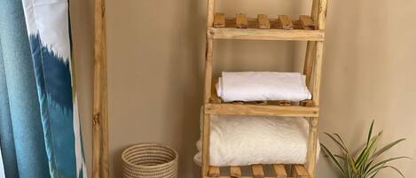 A wooden shelf with towels and a woven basket.