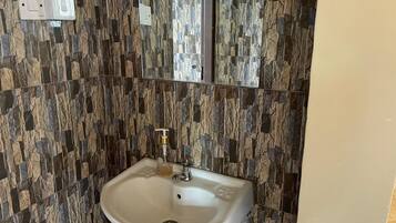 A bathroom with a stone-patterned wall, a white sink, and a mirror.