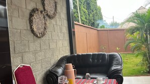Ein Essbereich im Freien mit Tisch für zwei, ausgestattet mit einer karierten Tischdecke, einer schwarzen Ledersitzbank und einem Korbwäscher mit Gewürzen.