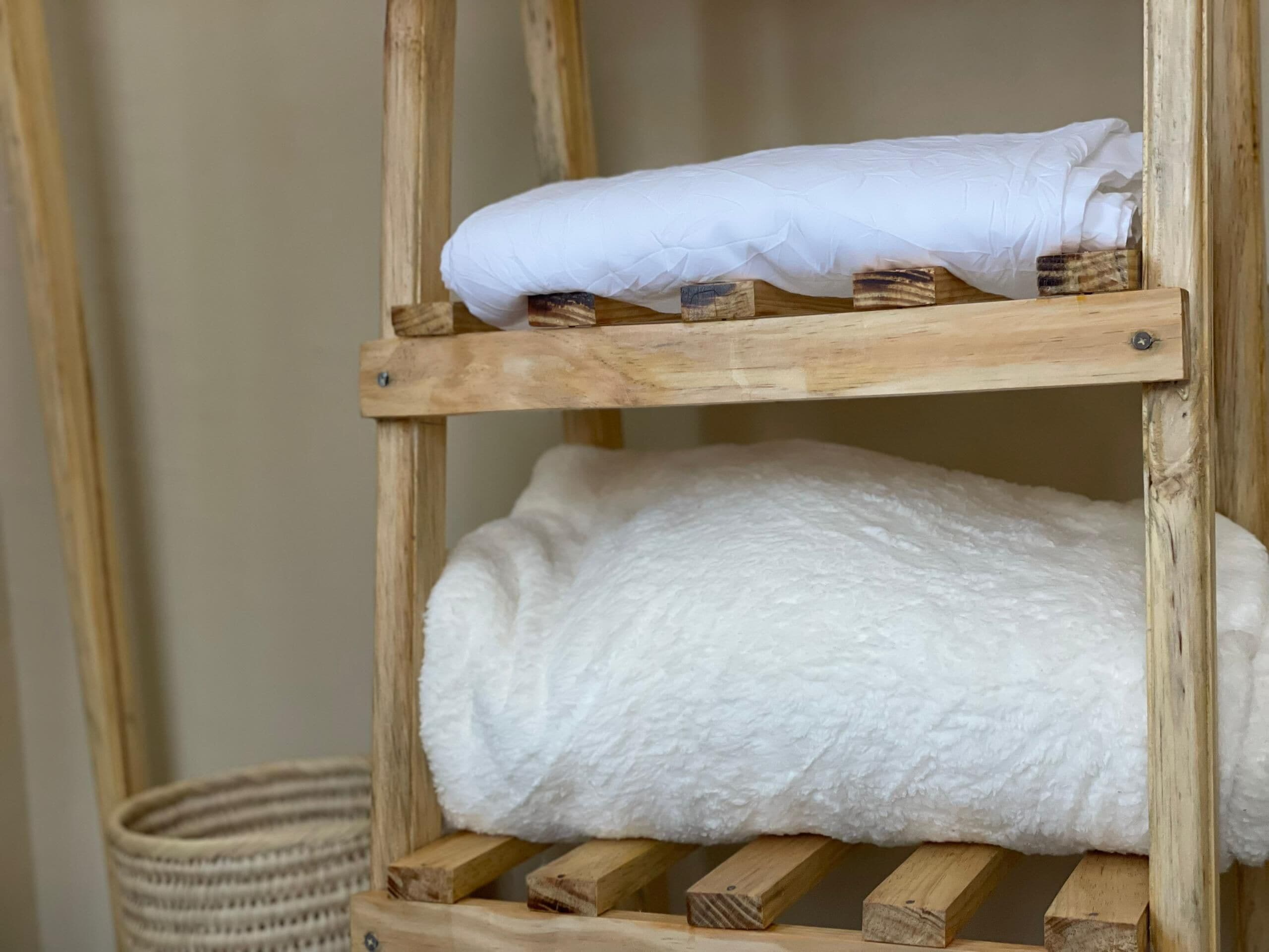 A wooden shelf with two white towels, one on top and one folded at the bottom.