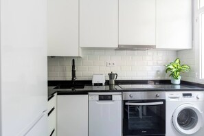 A modern kitchen with white cabinets, a Bosch dishwasher, a Bosch oven, and a washing machine. - Apartamento de 4 habitaciones en Santander (Santander)