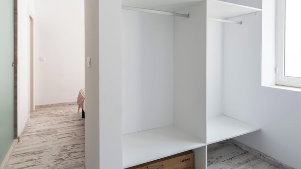Een kamer met een witte kast, een raam en een deur.