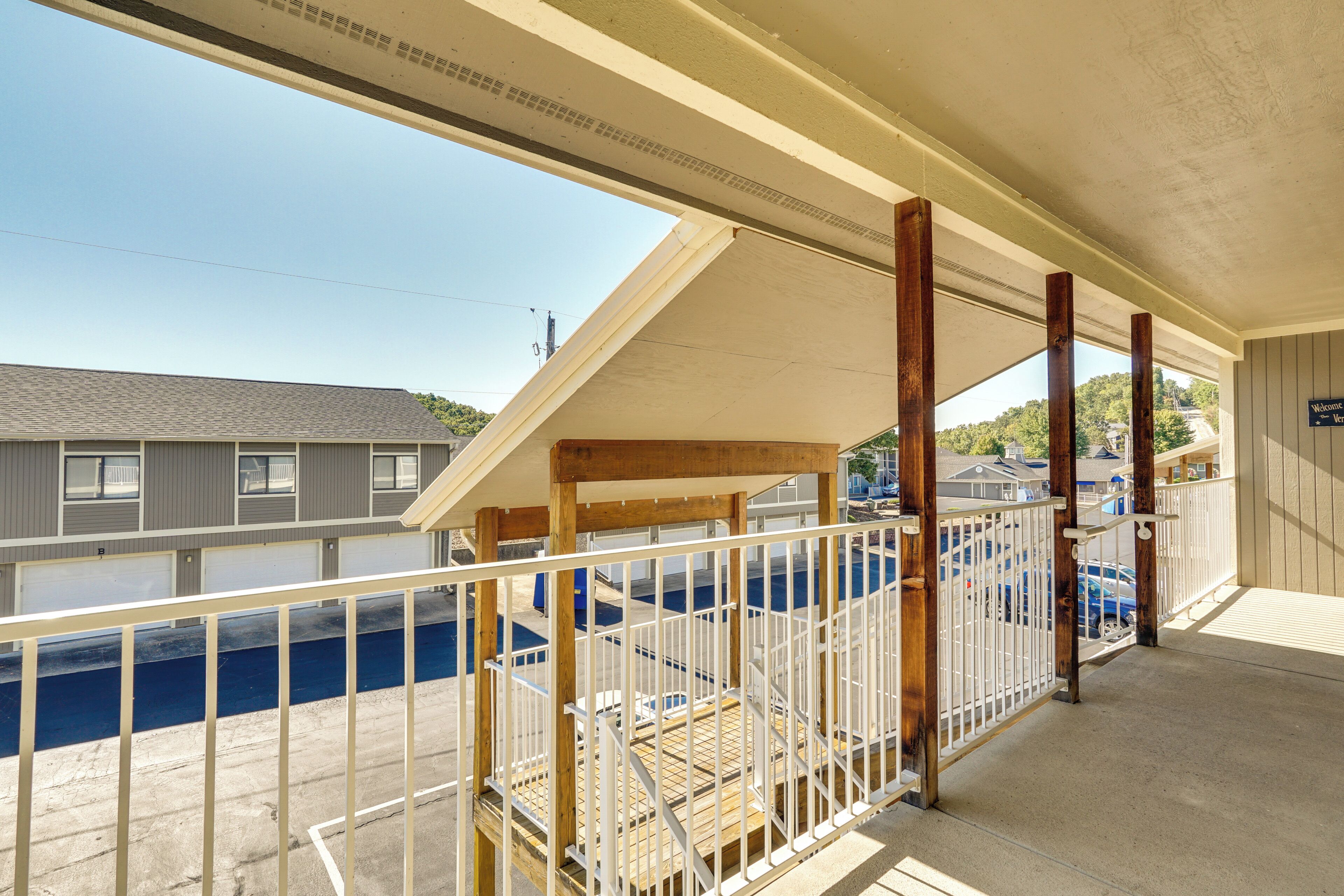 Un espacio al aire libre techado con piscina, terraza de madera y vista a un edificio al otro lado del agua.