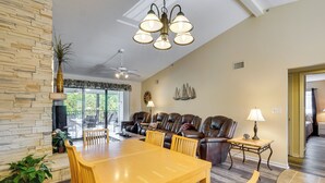A spacious living room with a wooden dining table, leather sofas, and a ceiling fan. - Waterfront Lazy Days Condo w/ Views & Pool Access! (Osage Beach)
