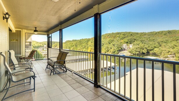 A balcony with chairs and a view of a lake and forest. - Waterfront Lazy Days Condo w/ Views & Pool Access! (Osage Beach)