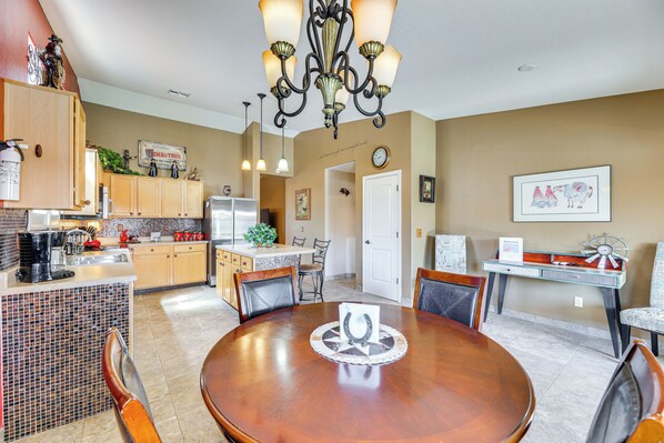A spacious kitchen with a dining area, featuring a chandelier, wooden cabinets, and a tiled backsplash. - Queen Creek Home w/ Pool: Swim, Golf & Explore! (San Tan Valley)