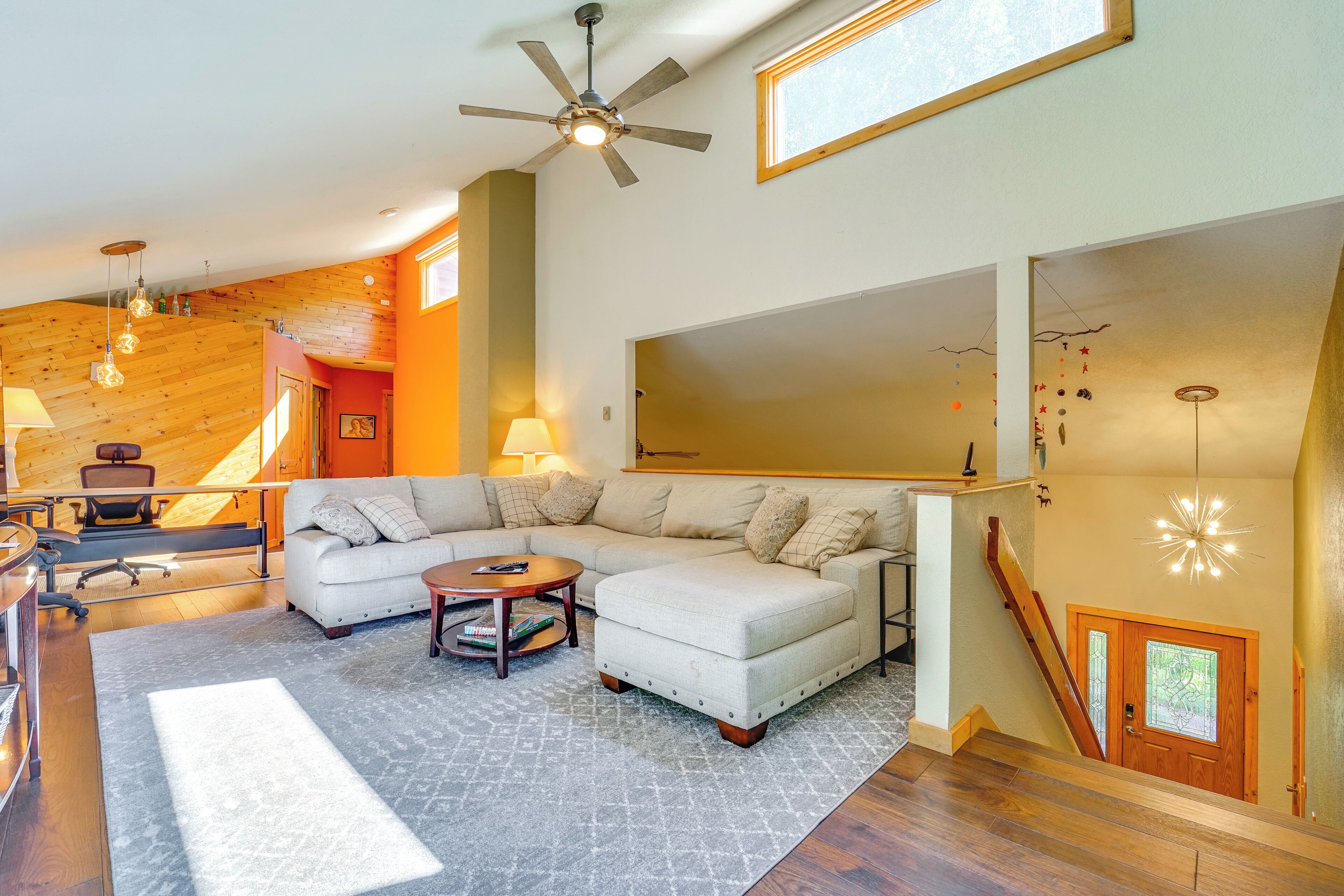 A spacious living room with a sectional sofa, a coffee table, and a ceiling fan.