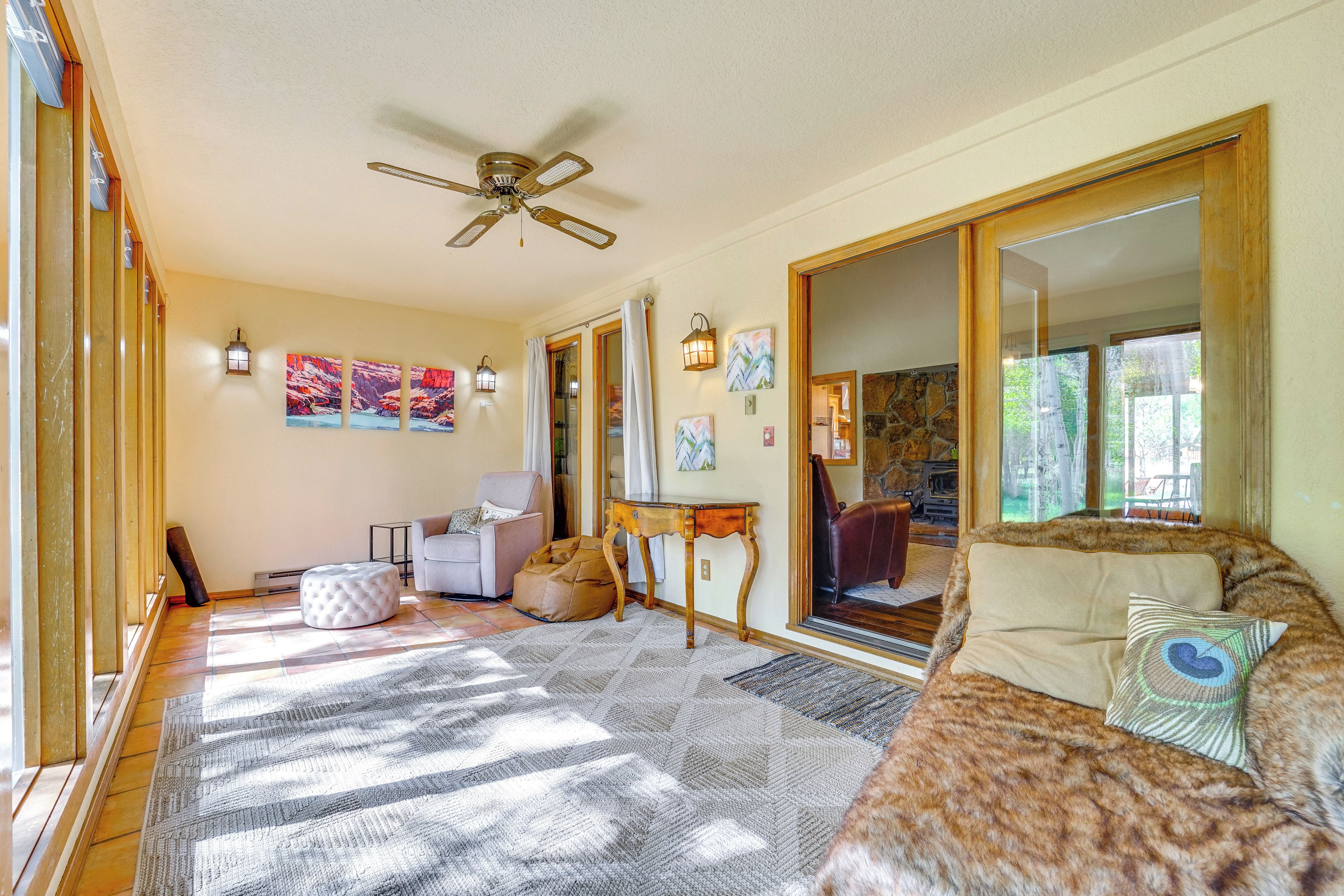 A spacious living room with a large mirror, a ceiling fan, and a sofa with a fur throw.