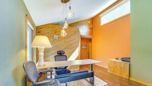 A modern room with a wooden sloped ceiling, a desk with a lamp, a chair, and a small wooden cabinet. - Dog-friendly Home w/ Hot Tub & Decks in Durango! (Durango)