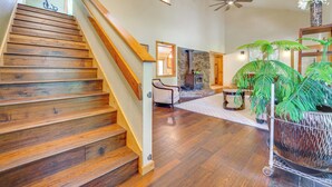 A wooden staircase leading to a living area with a fireplace, a ceiling fan, and a potted fern. - Dog-friendly Home w/ Hot Tub & Decks in Durango! (Durango)